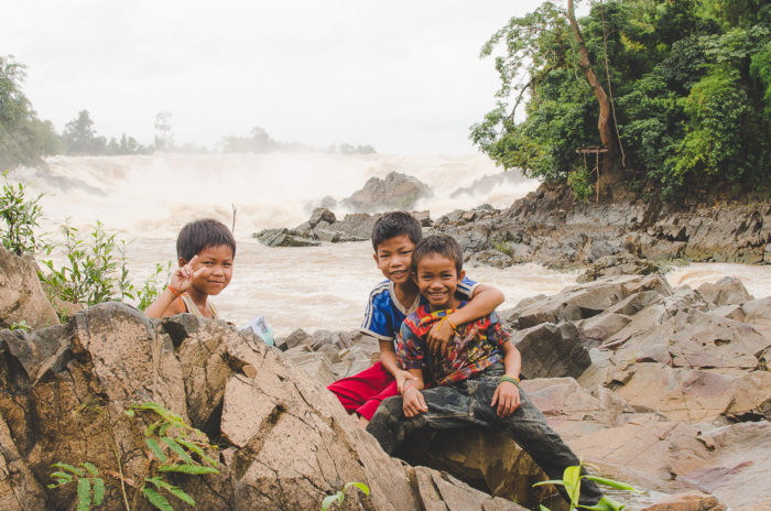 Kids posing in front of the camera and waterfall behind in Laos taken by Milie Del