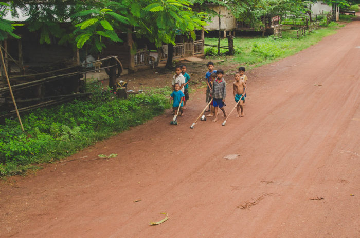 kids playing outside on the dusty road in Boloven in Laos taken by Milie Del