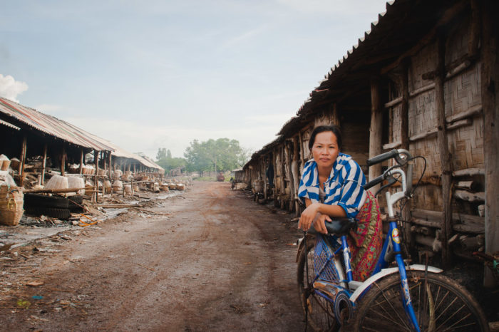 Portrait of a woman and her bike in a salt factory in Laos taken by Milie Del