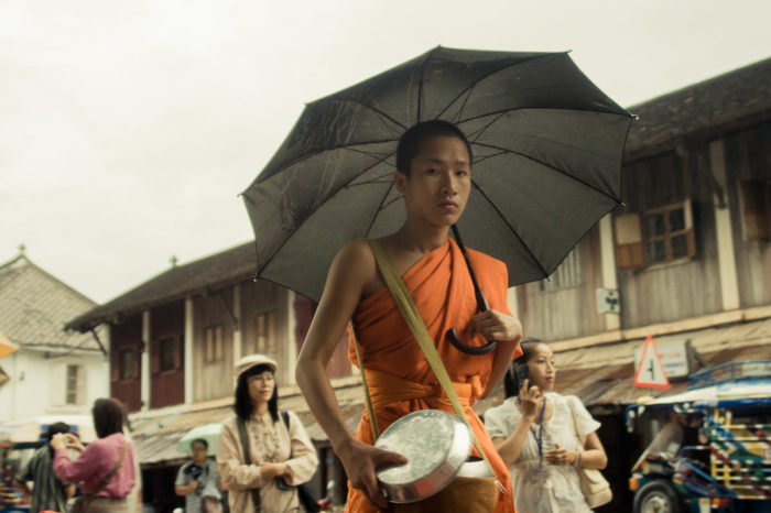 Portrait of a monk with an umbrella during Alms Giving to the Monks in Luang Prabangin Laos taken by Milie Del