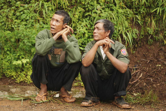 two men in military outfits sitting on the side of the orad to Luang prabang in Laos taken by Milie Del