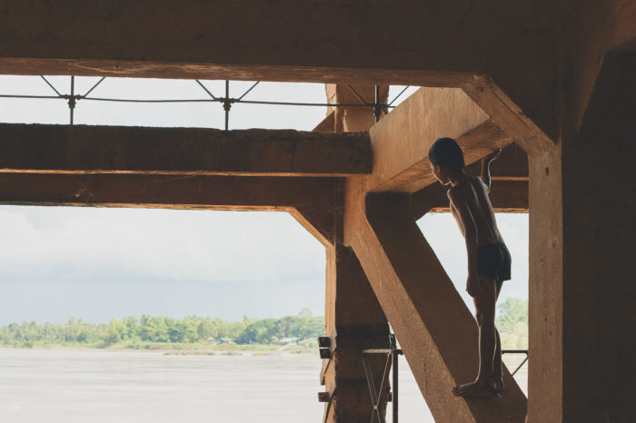 Little boy watching the sun in a abandoned factory in Laos taken by Milie Del