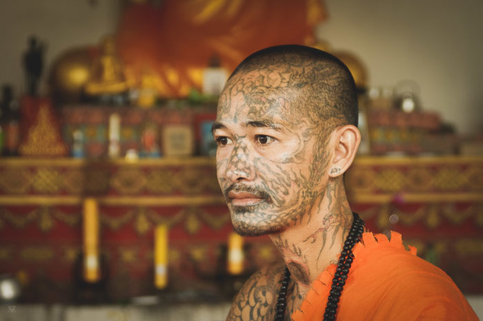 portrait of a tatoued Monk in orange outfit Laos taken by Milie Del