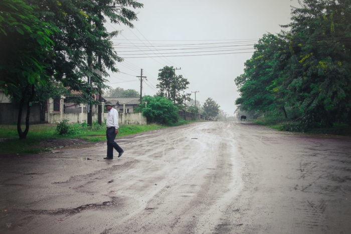 Man crossing the road near the salt factory under the rain near Vientiane Laos taken by Milie Del
