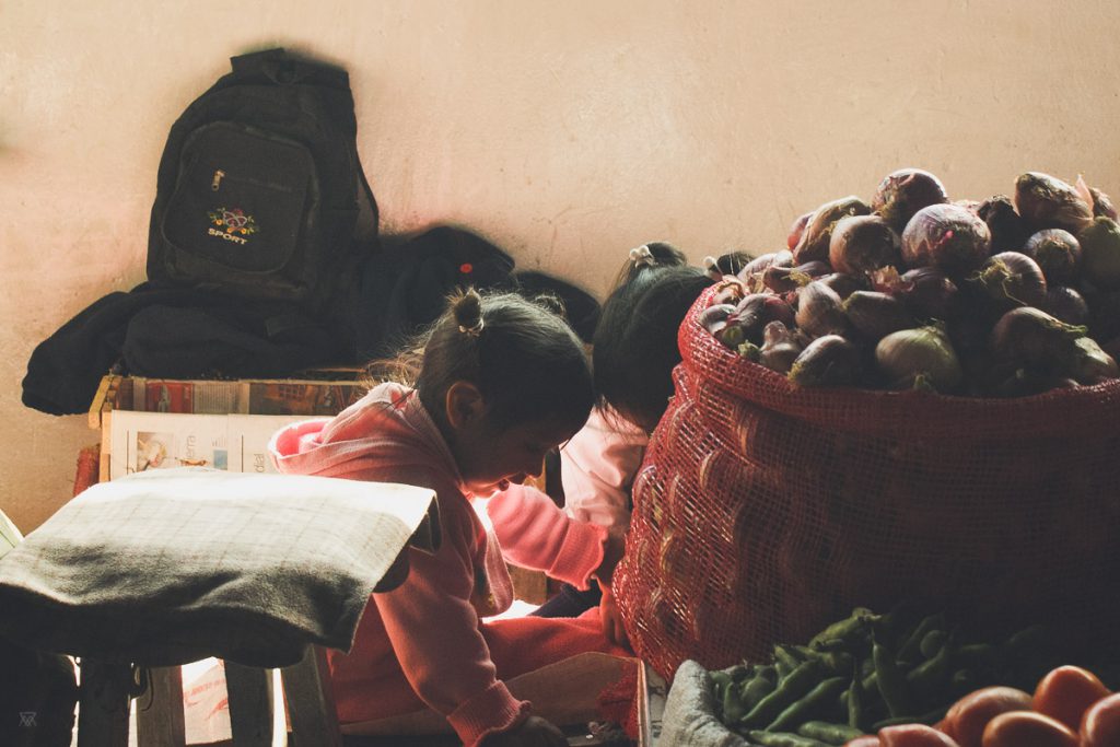 photo of peruvian girls playing behing baskets of onions in the cuzco market in Peru