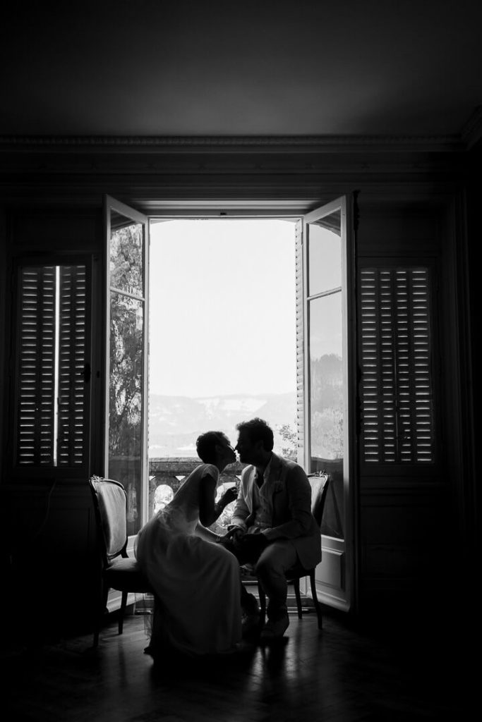 Bride and groom kissing in the window light