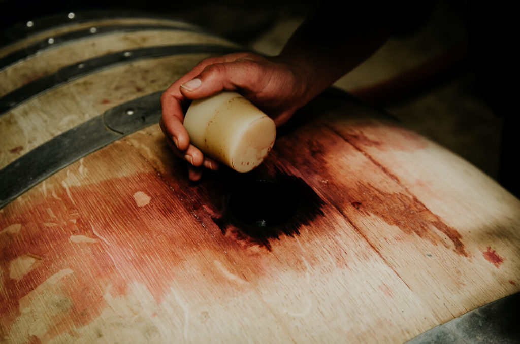 Main ouvrant le bouchon d'un tonneau de vin