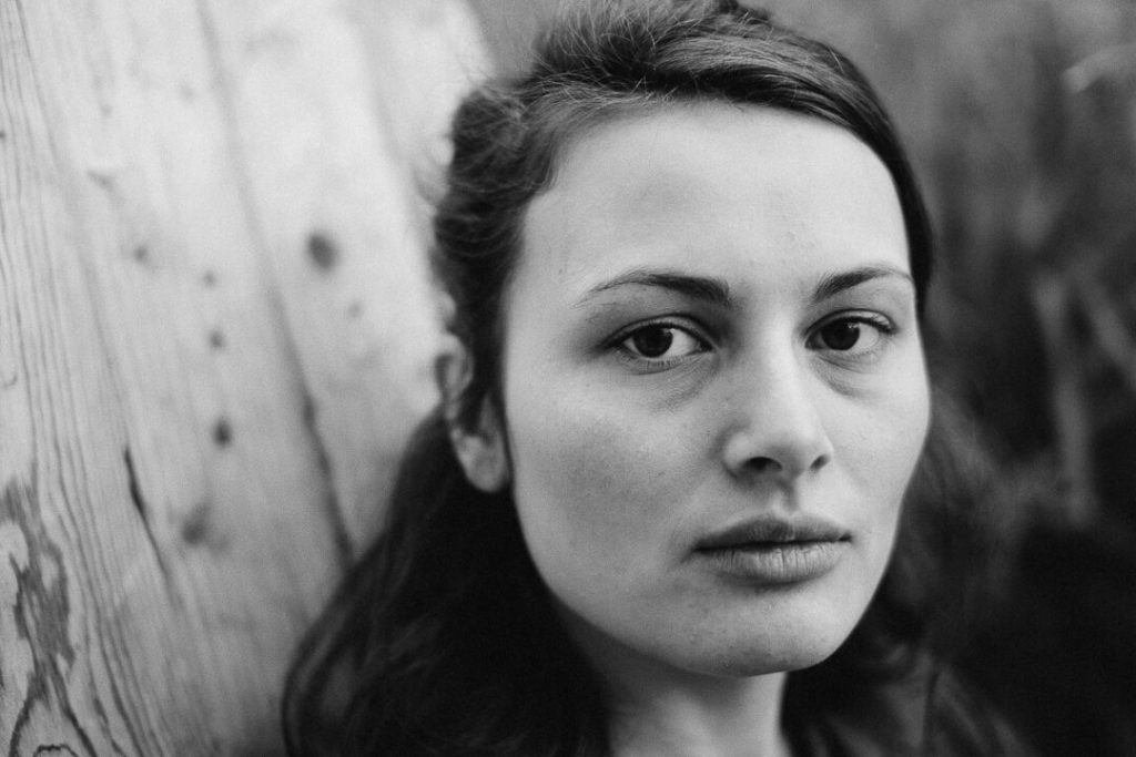 portrait en noir et blanc Manon Gilbert assise dans une chaise en bois