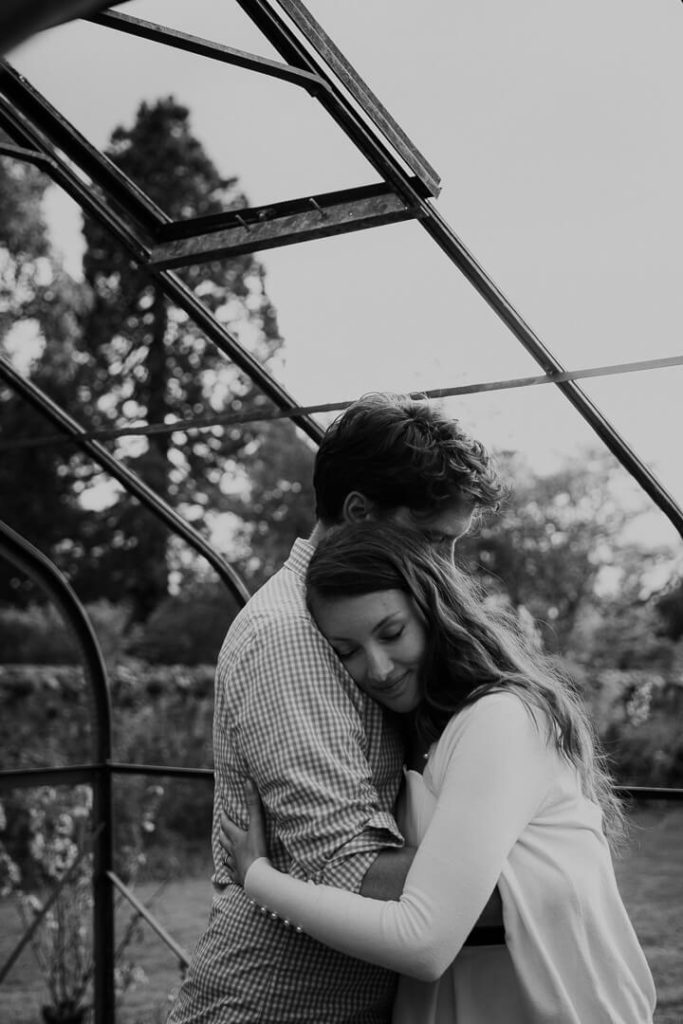 black and white photography couple hugging greenhouse