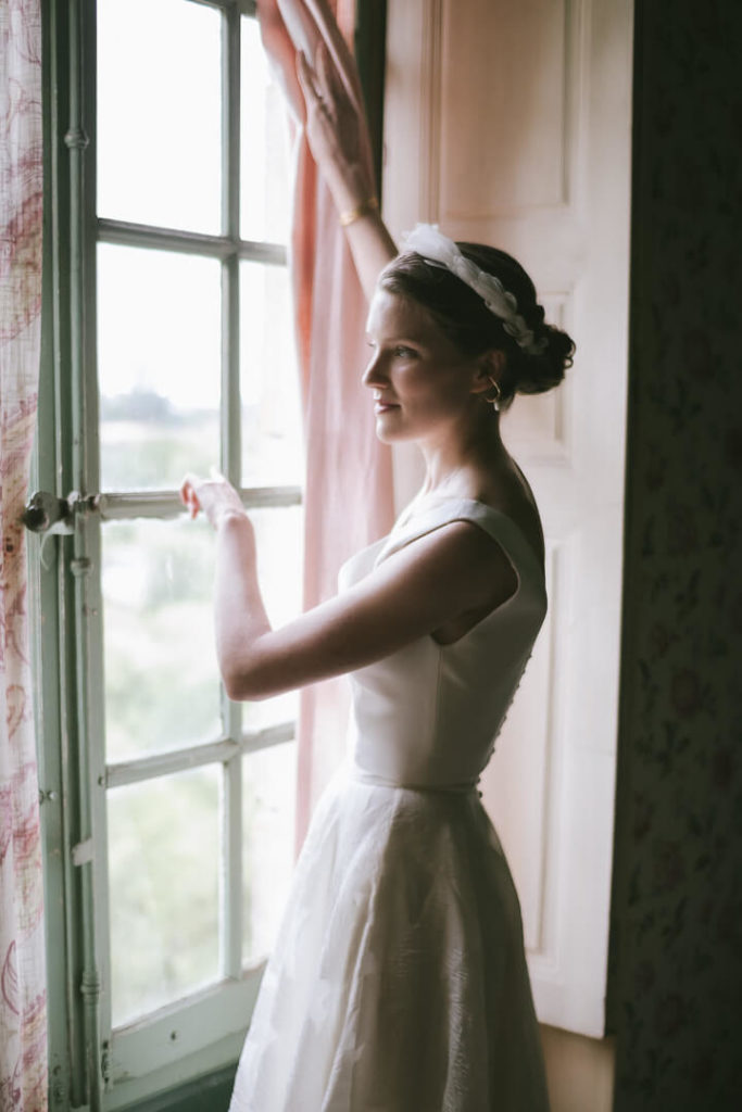 beautiful bride opening window at Château de Sully